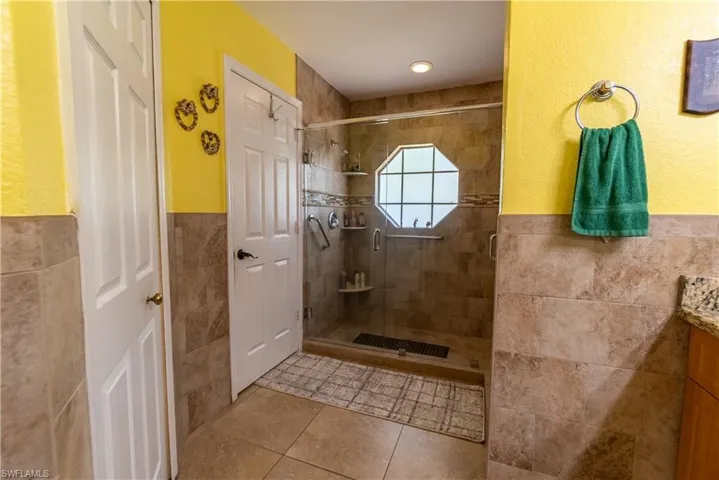 Bathroom with tile walls, vanity, a stall shower, tile patterned flooring, and wainscoting