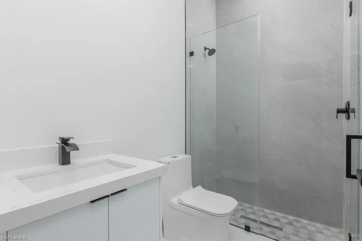 Bathroom featuring toilet, a marble finish shower, and vanity