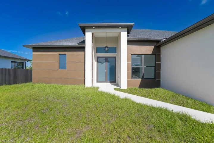 Rear view of house with a lawn, roof with shingles, fence, french doors, and stucco siding