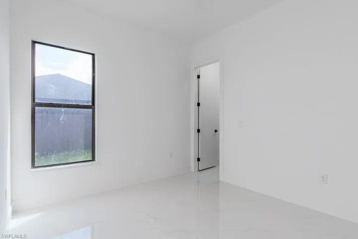 Empty room with marble finish floor, plenty of natural light, and baseboards