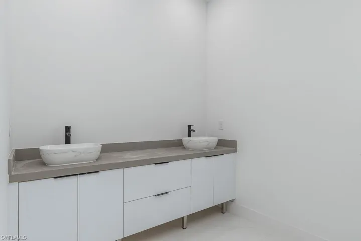 Full bathroom featuring marble finish floor, a sink, baseboards, and double vanity