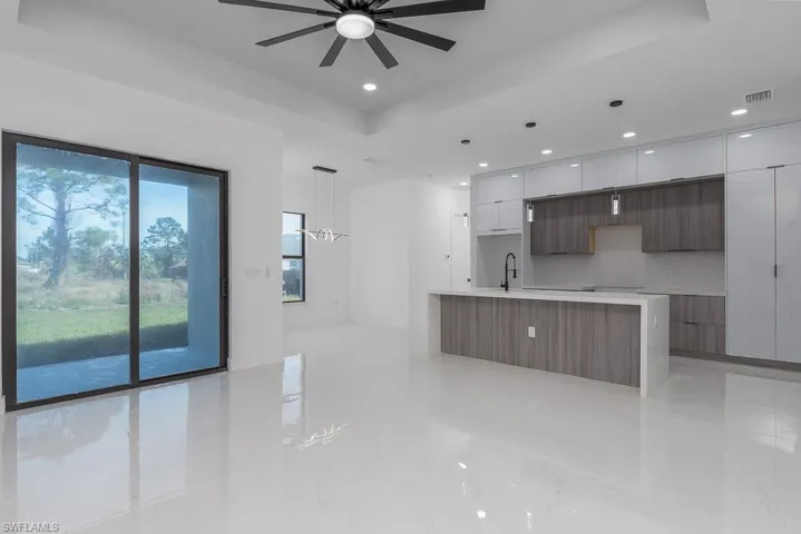 Kitchen featuring a tray ceiling, a large island, white cabinetry, a sink, and modern cabinets