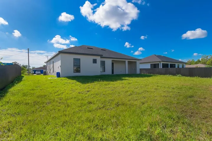 Back of property with a yard, fence, and stucco siding