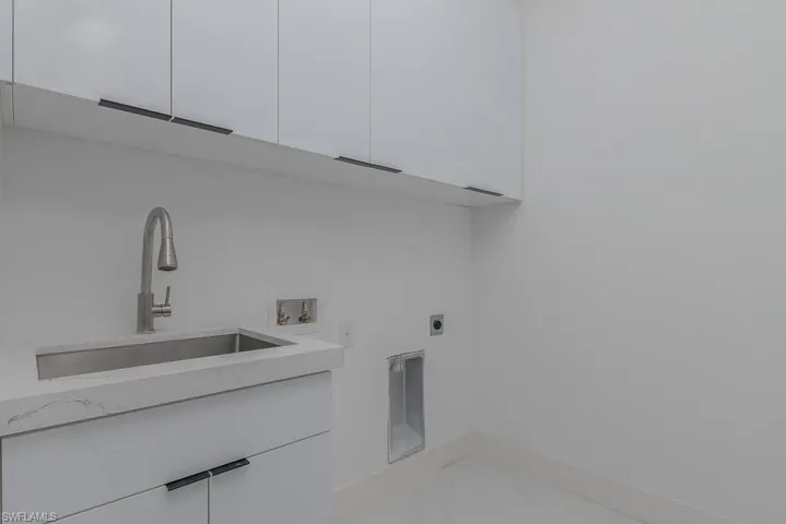 Laundry area featuring cabinet space, hookup for a washing machine, marble finish floor, hookup for an electric dryer, and a sink