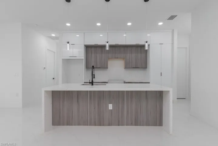 Kitchen with white cabinets, a large island, modern cabinets, marble finish floor, and a sink
