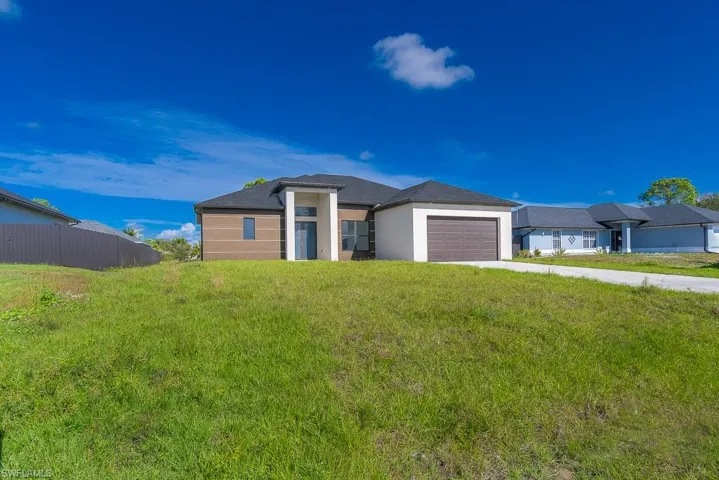 Prairie-style house featuring an attached garage, driveway, fence, and a front lawn