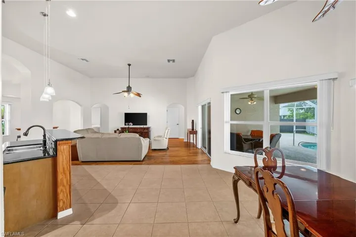 Living room featuring healthy amount of natural light, a ceiling fan, arched walkways, light tile patterned floors, and a high ceiling