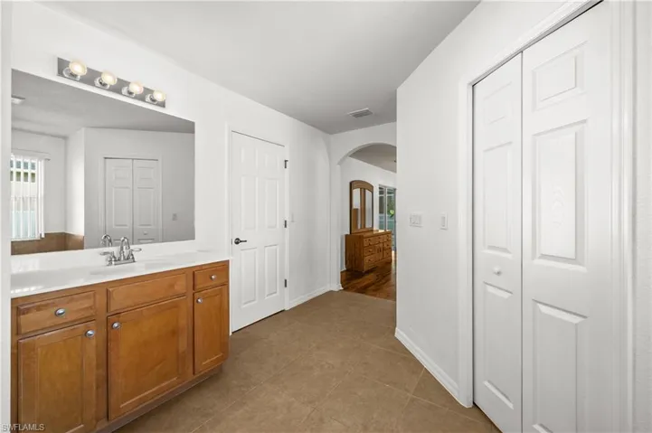 Full bath featuring a closet, vanity, and dark tile patterned floors