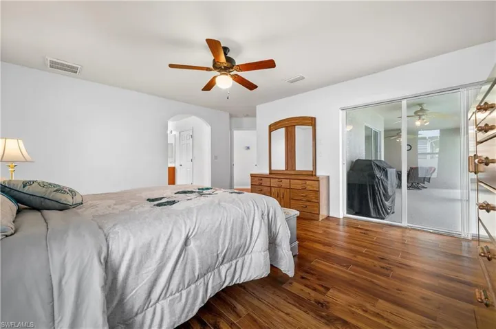 Bedroom with wood finished floors, ceiling fan, and arched walkways
