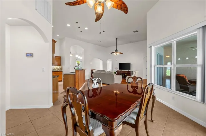 Dining area featuring arched walkways, light tile patterned floors, a ceiling fan, and recessed lighting
