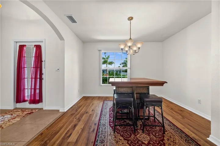 Dining space featuring dark wood-style flooring, arched walkways, and a chandelier