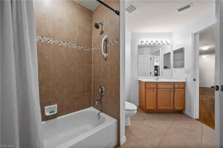 Full bath with shower / bath combo with shower curtain, light tile patterned floors, and vanity