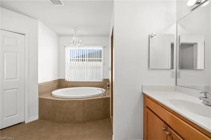 Bathroom featuring vanity, a garden tub, and light tile patterned floors