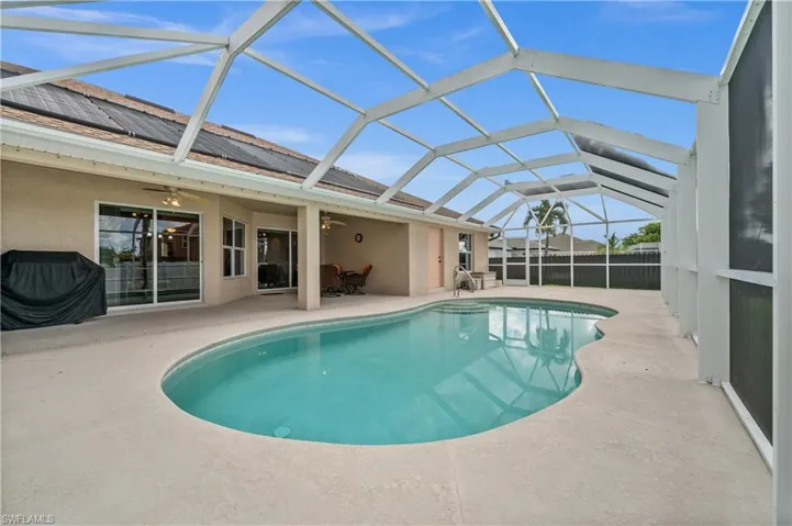 View of swimming pool featuring ceiling fan, a sunroom, glass enclosure, a patio, and grilling area