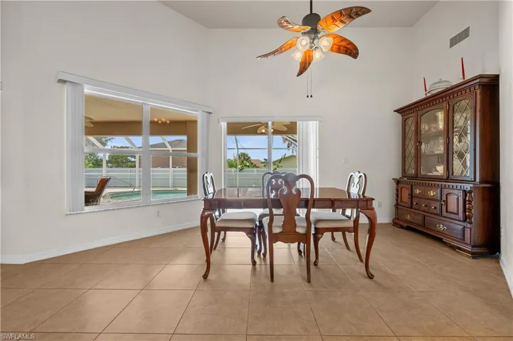 Dining area with a high ceiling, light tile patterned flooring, healthy amount of natural light, and ceiling fan