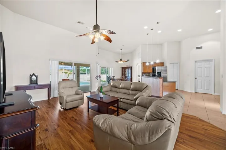 Living area with a towering ceiling, ceiling fan, light wood-type flooring, and recessed lighting