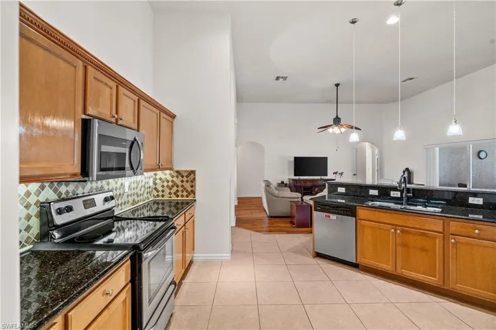 Kitchen featuring brown cabinetry, appliances with stainless steel finishes, and dark stone countertops