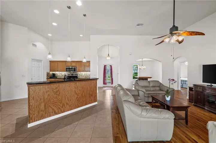 Living room with a towering ceiling, ceiling fan, arched walkways, recessed lighting, and light tile patterned floors