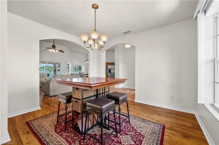 Dining room featuring arched walkways, a ceiling fan, light wood-type flooring, and a chandelier