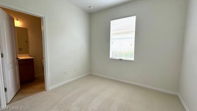 Unfurnished bedroom featuring ensuite bath and carpet flooring