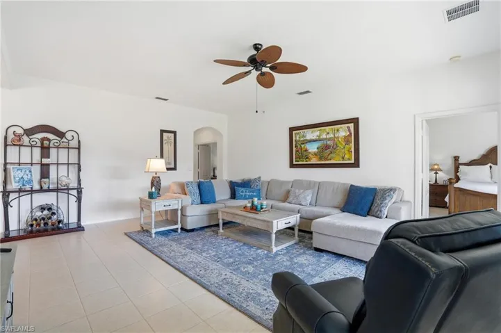 Living area with arched walkways, a ceiling fan, and light tile patterned floors