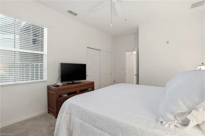 Bedroom featuring light colored carpet, ceiling fan, and a closet