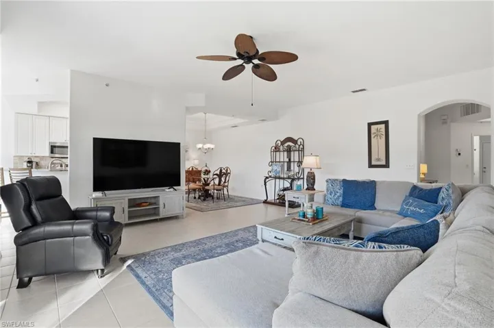 Living room with ceiling fan, light tile patterned floors, and arched walkways