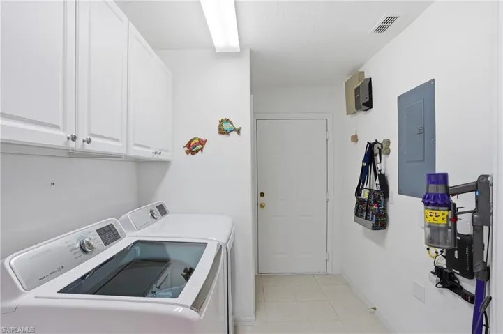 Laundry area featuring electric panel, washing machine and dryer, and cabinet space