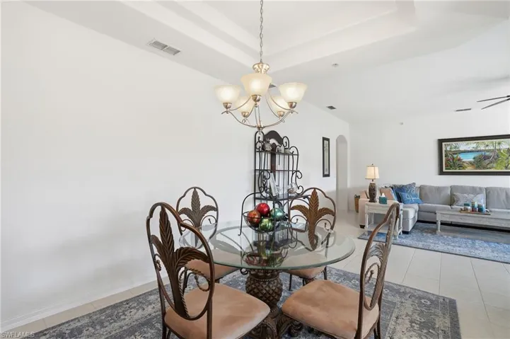 Dining space featuring arched walkways, light tile patterned floors, a chandelier, and a raised ceiling