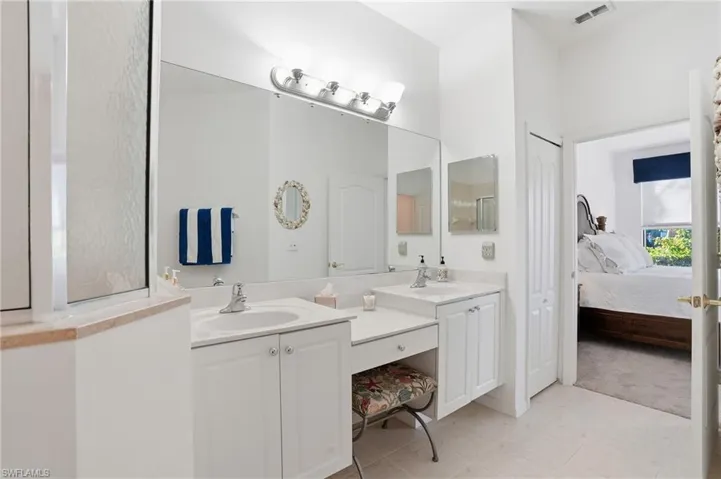 Ensuite bathroom with double vanity and light tile patterned flooring