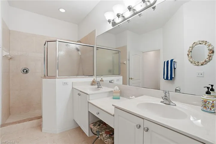 Bathroom featuring a walk in shower, double vanity, and light tile patterned floors