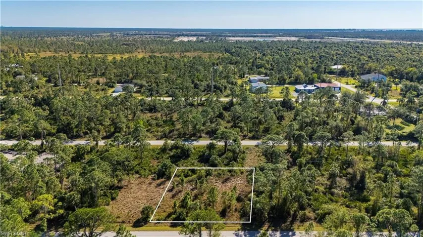 Aerial view of property and surrounding area featuring property boundaries highlighted and a forest