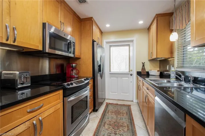 Kitchen featuring sink, stainless steel appliances, light tile patterned floors, and hanging light fixtures