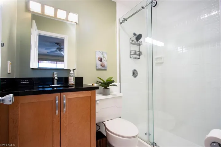 Bathroom featuring toilet, walk in shower, and vanity