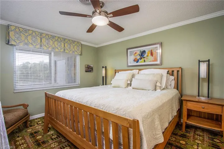 Bedroom featuring ceiling fan, crown molding, and a textured ceiling