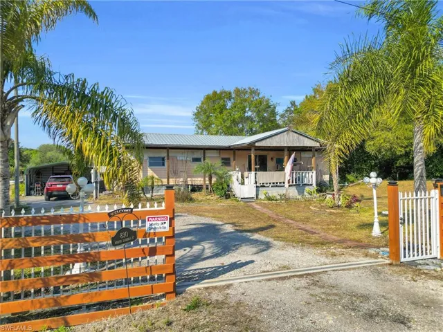 Bungalow-style home featuring a metal roof, a carport, driveway, and a porch