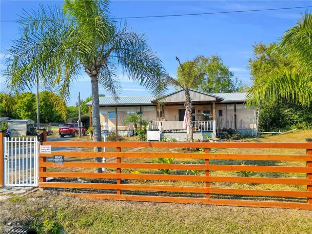 Bungalow-style house featuring a fenced front yard, a metal roof, and a gate