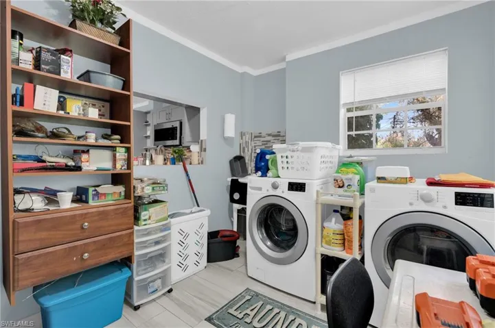 Washroom featuring crown molding and washer and clothes dryer