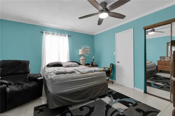 Bedroom featuring a ceiling fan, light tile patterned floors, crown molding, and a closet