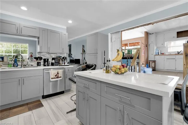 Kitchen with gray cabinetry, backsplash, and dishwasher