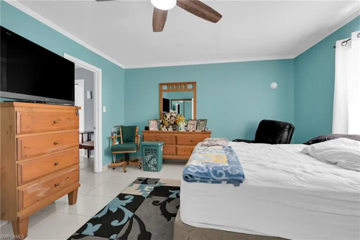 Bedroom with ornamental molding, a ceiling fan, and light tile patterned floors
