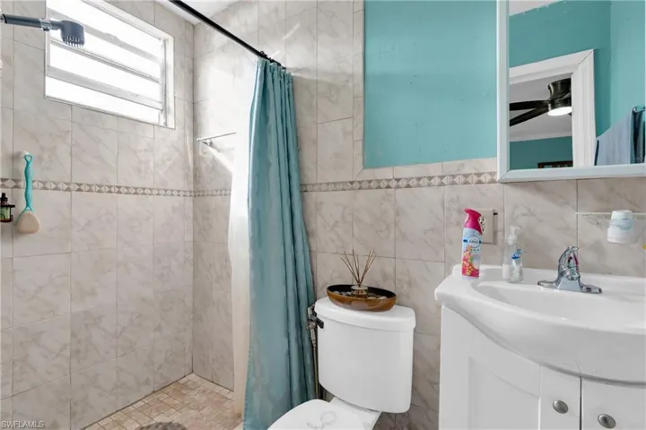 Bathroom featuring a stall shower, vanity, and tile walls