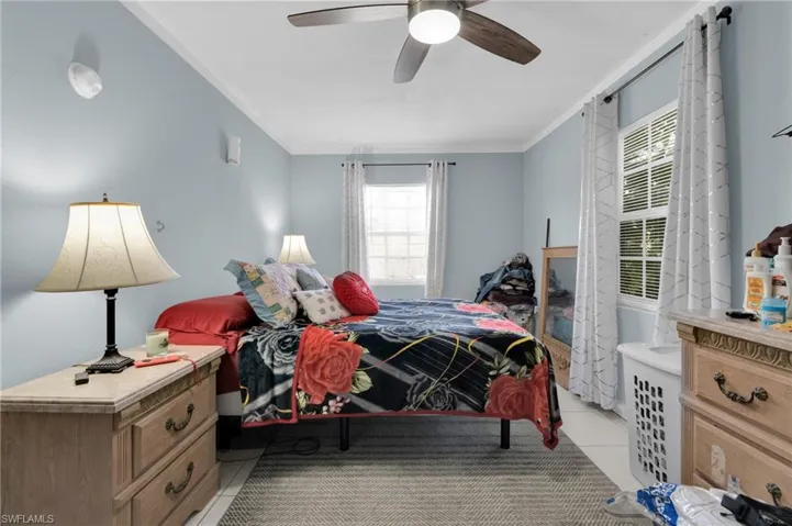 Bedroom featuring light tile patterned floors, ceiling fan, and ornamental molding