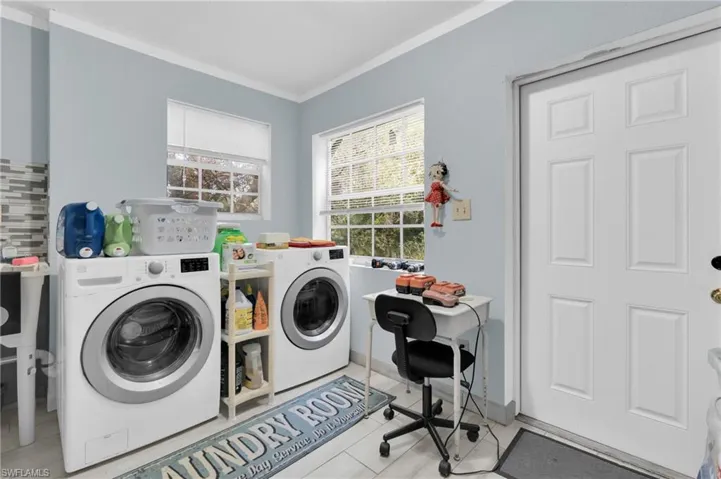 Laundry room with crown molding and washer and dryer