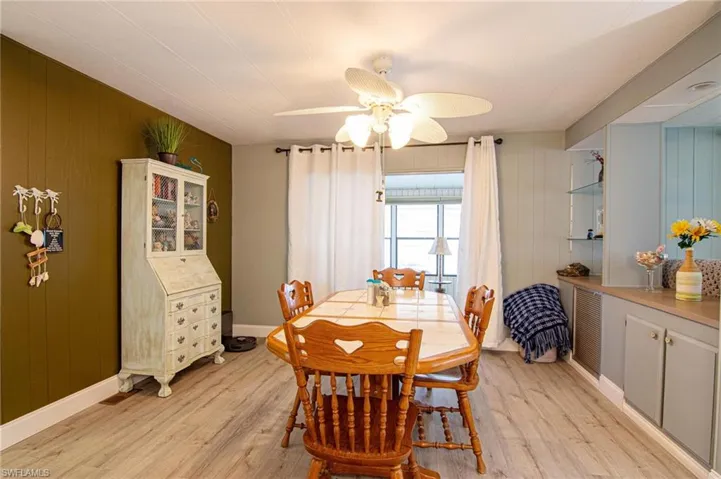 Dining area featuring light wood finished floors, ceiling fan, wooden walls, and baseboards