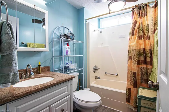 Bathroom with shower / bath combination with curtain, toilet, vanity, and wood finished floors