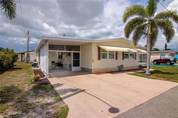 Manufactured / mobile home with concrete driveway, a carport, central air condition unit, and a front yard