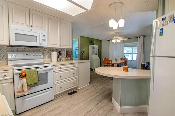 Kitchen featuring white appliances, light wood-style flooring, light countertops, and ceiling fan