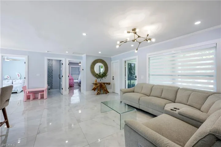 Living room featuring crown molding, ceiling fan, and hanging lights