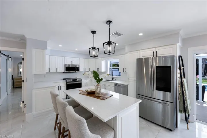 Kitchen with stainless steel appliances, a barn door, a center island, ornamental molding, and a breakfast bar area